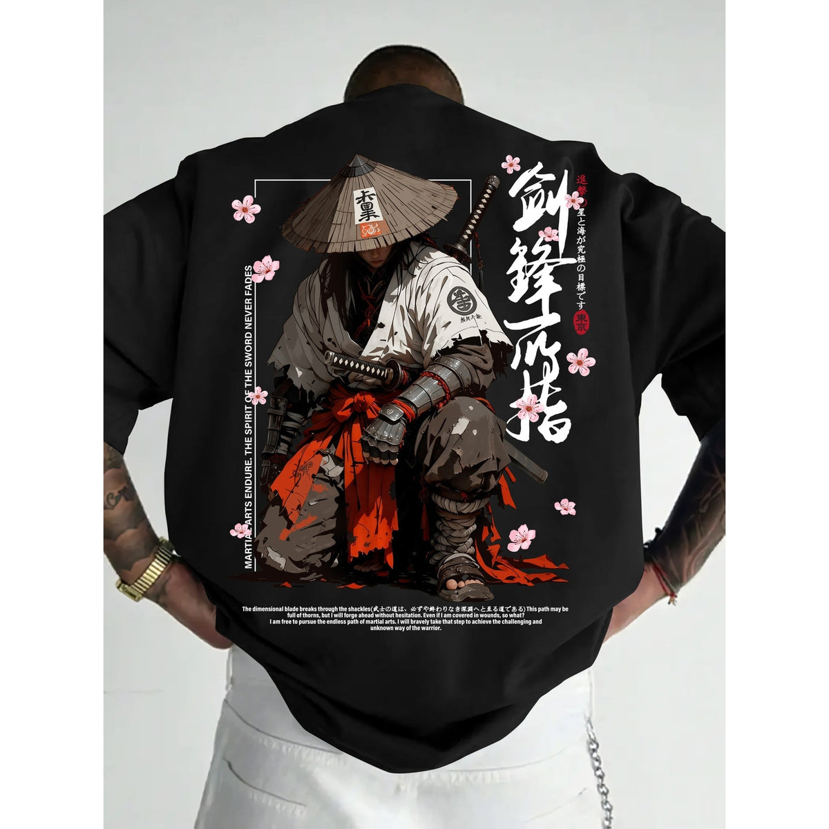 A man wearing a black t-shirt with a large graphic print on the back, featuring an anime-style samurai in a conical hat with cherry blossoms and Japanese text.