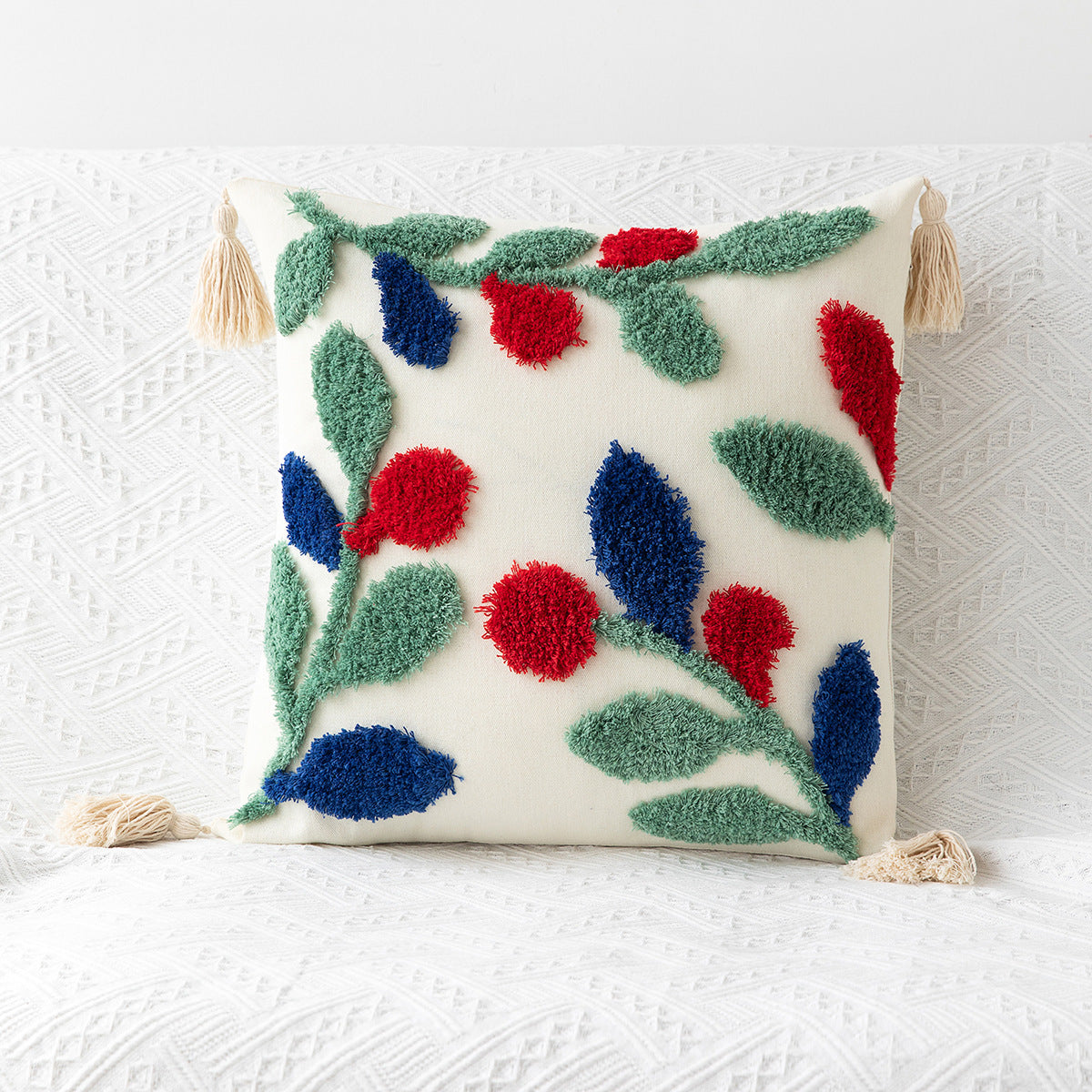 Decorative pillow with floral patterns and tassels on a textured white background