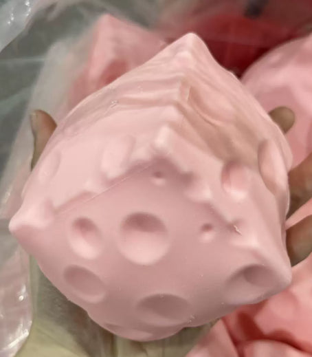 Pink silicone cheese squishy product with textured surface on a blurred background