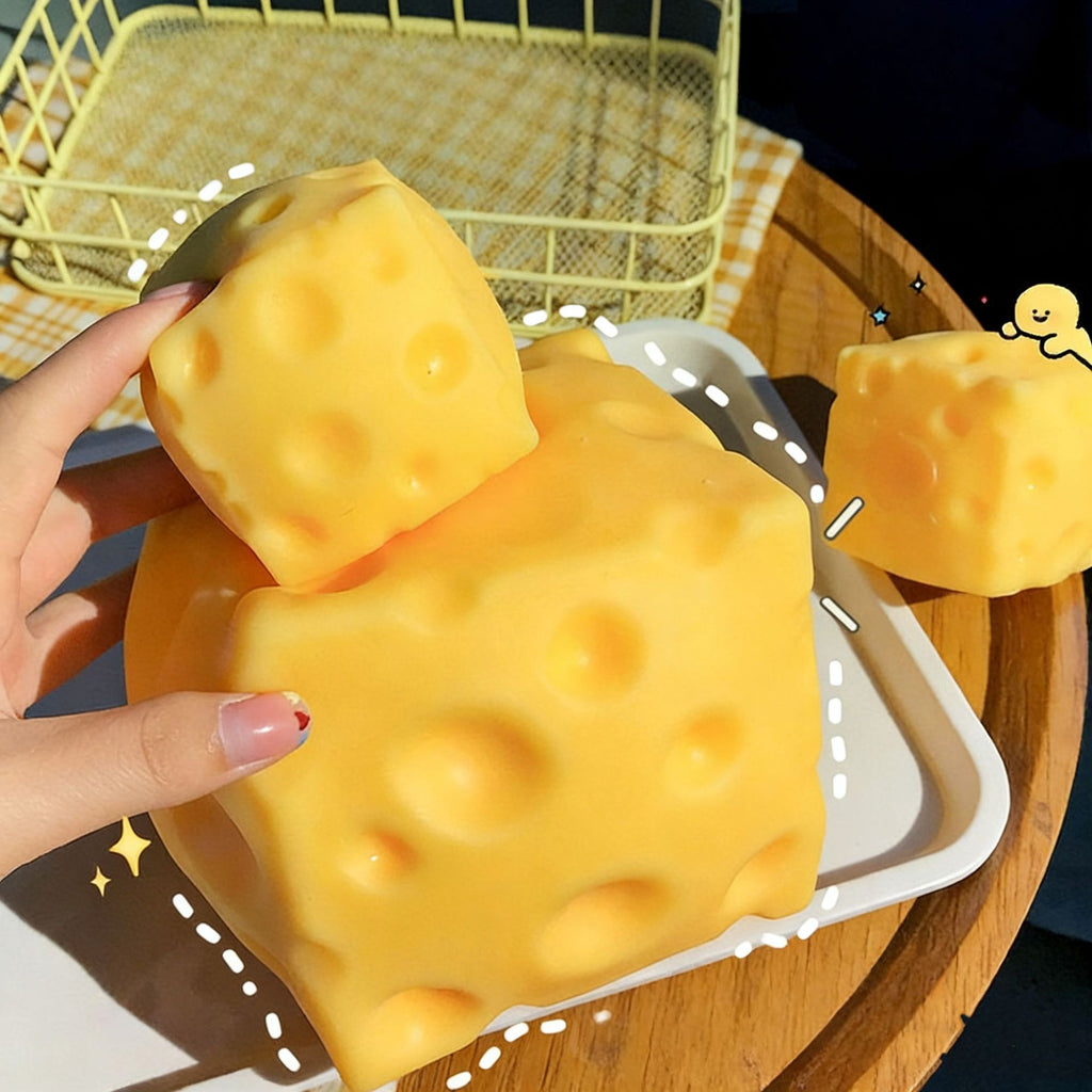 Yellow cheese-shaped squishy with a hand holding it, on a wooden surface.