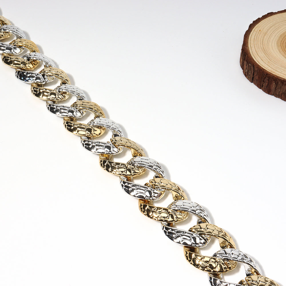 Gold and silver chain bracelet on a white background with a wooden slice.