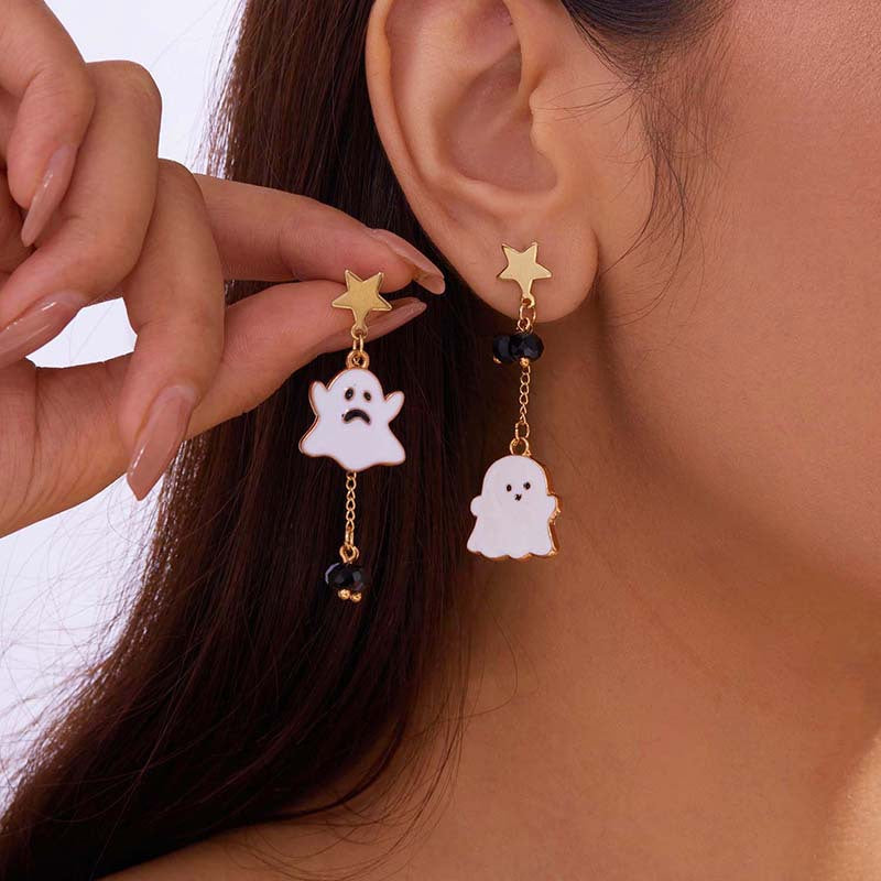 Ghost-shaped earrings with star and bead details worn by a person.
