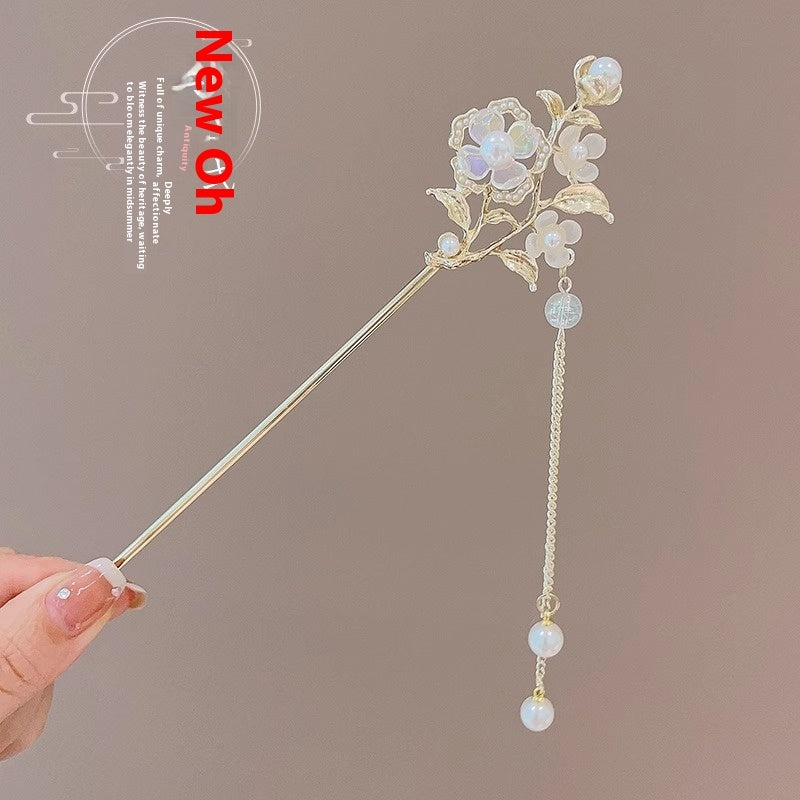 Decorative hair stick with floral design and beads held by a hand against a brown background.