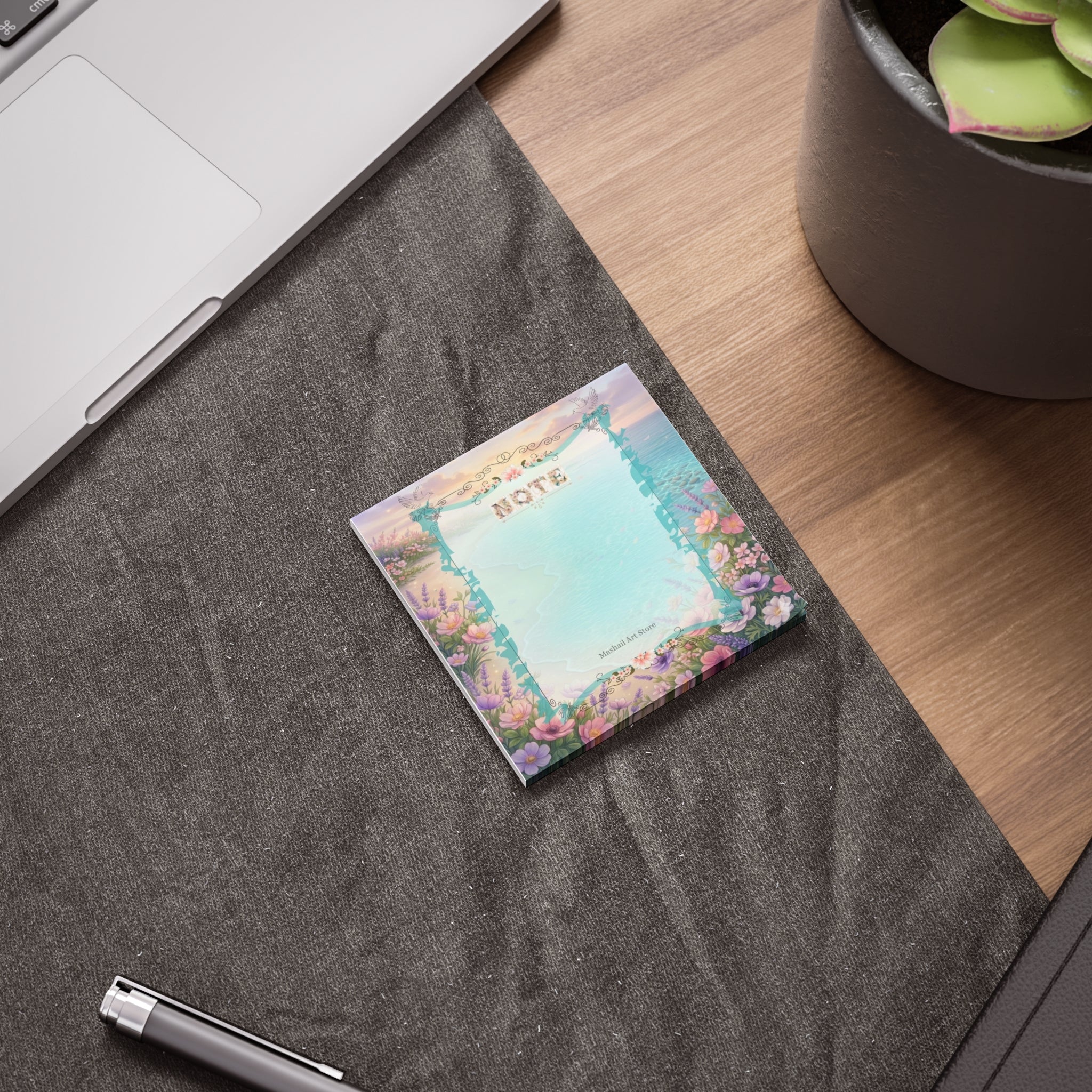 Notebook with floral design on a desk next to a laptop and pen