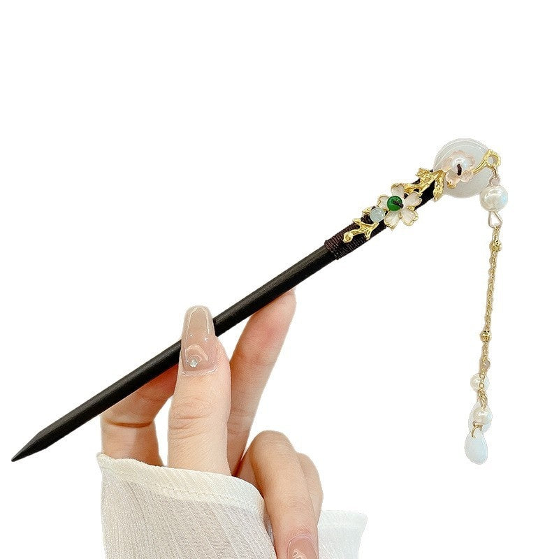 Decorative hair stick with beads and a hand holding it on a white background