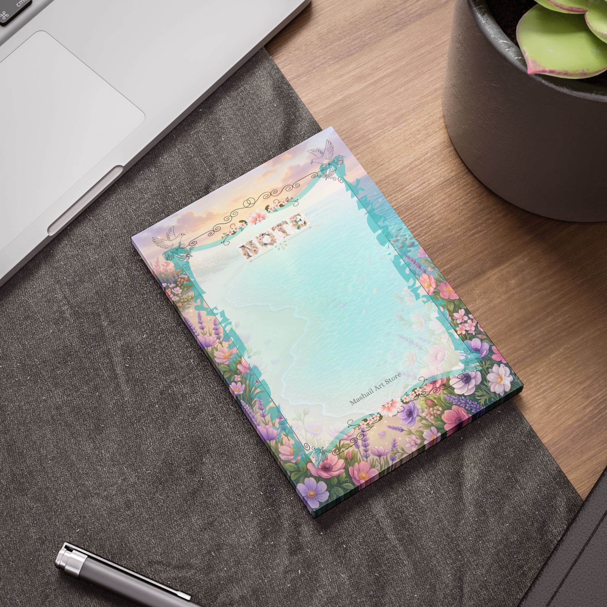 Floral notepad on a desk with a pen and laptop