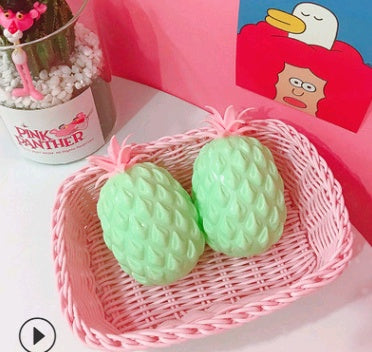 Two green Pineapple squishy toy in a pink basket with a 'Pink Panther' container in the background.