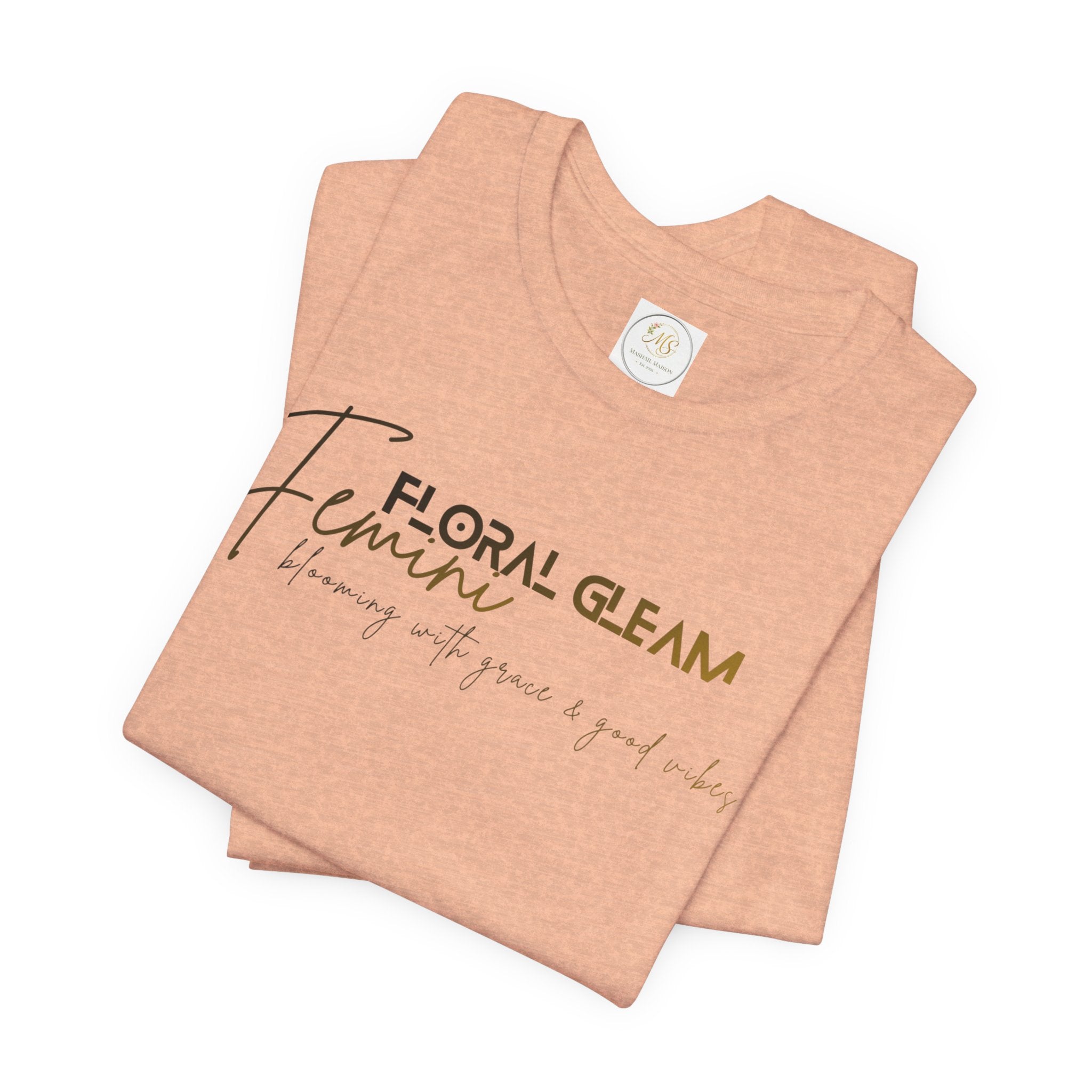 Folded peach-colored t-shirt with 'Floral Gleam' branding on a white background