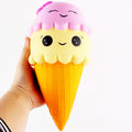 Squishy toy shaped like an ice cream cone with a pink top held by a hand on a white background