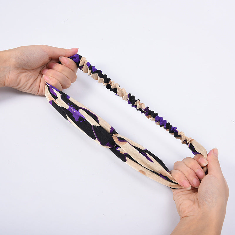 Hands holding a headband with purple and beige pattern on a white background