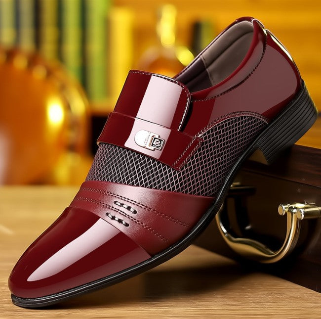 Shiny red loafer shoe on a wooden surface with a blurred background