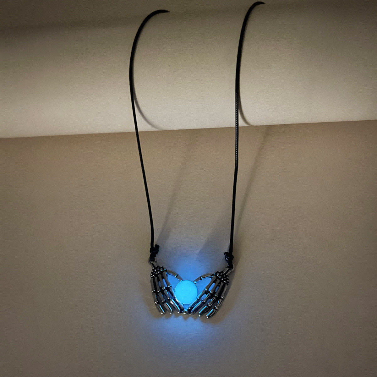 Necklace with glowing blue pendant on a beige background