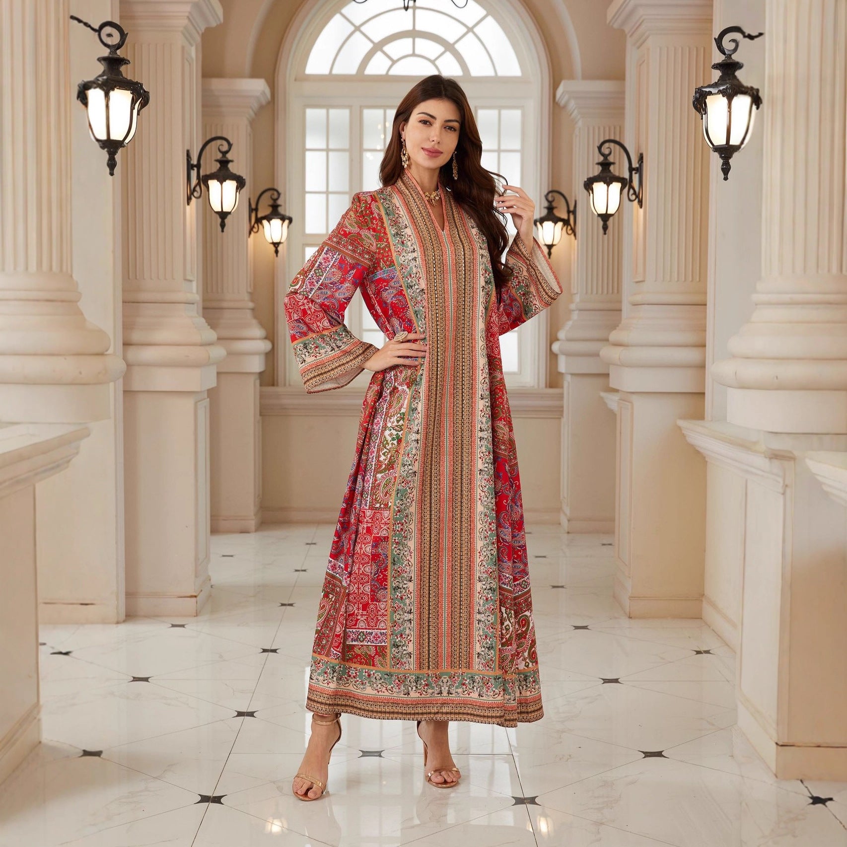 Woman in a patterned dress standing in an elegant hallway with columns and lights.