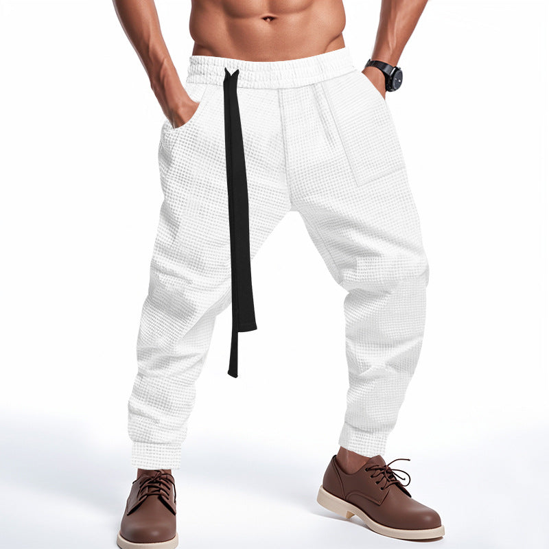 White textured pants with a black stripe worn by a person on a white background