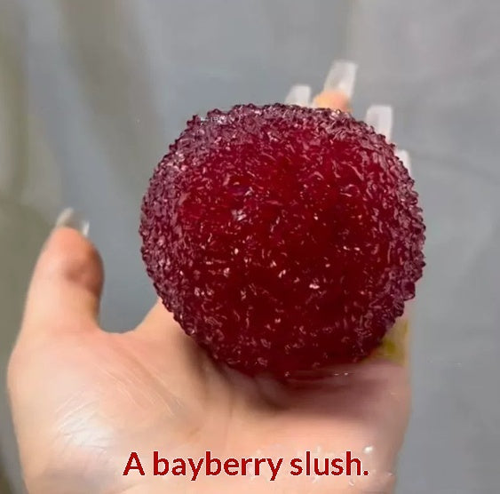 Hand holding a bayberry slush Squishy ball with a blurred background