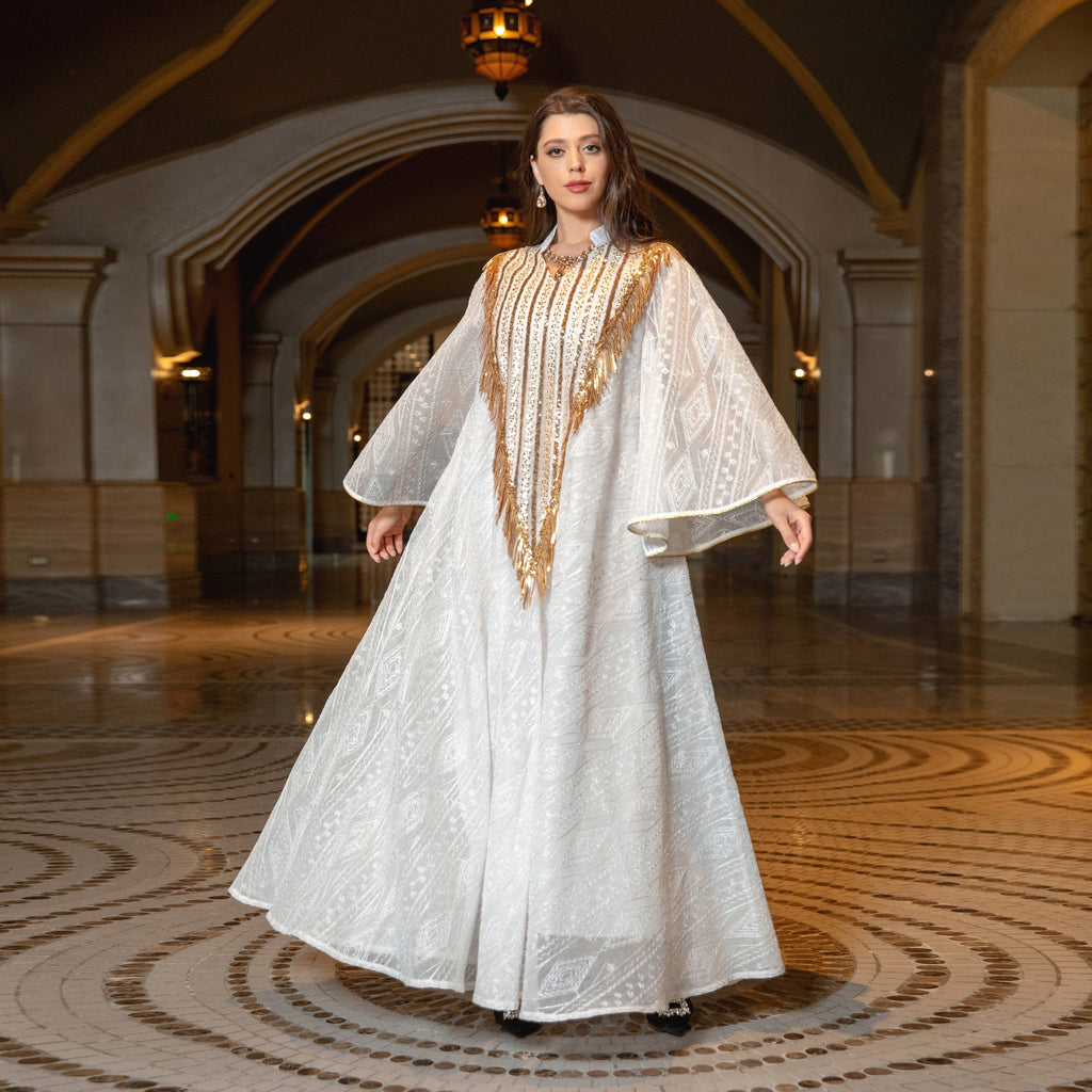 Woman in a white and gold dress standing in an elegant hall with arched ceilings.