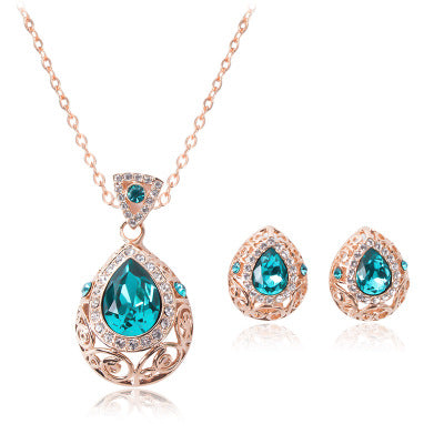 Jewelry set with rose gold necklace and earrings featuring blue teardrop stones on a white background