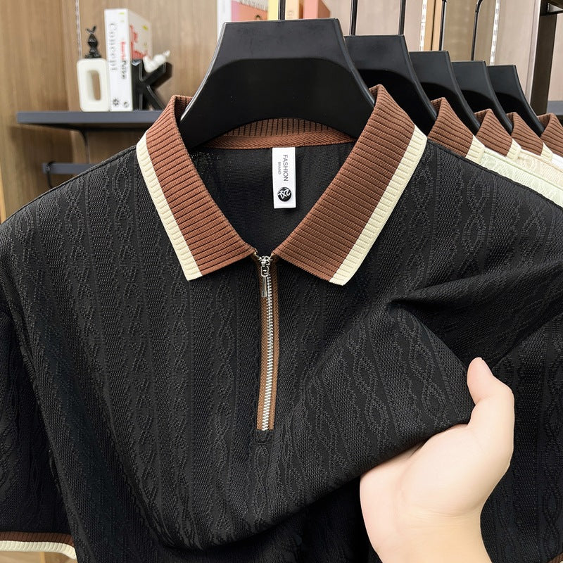 Black sweater with brown and beige collar held by a hand, with a blurred indoor background.