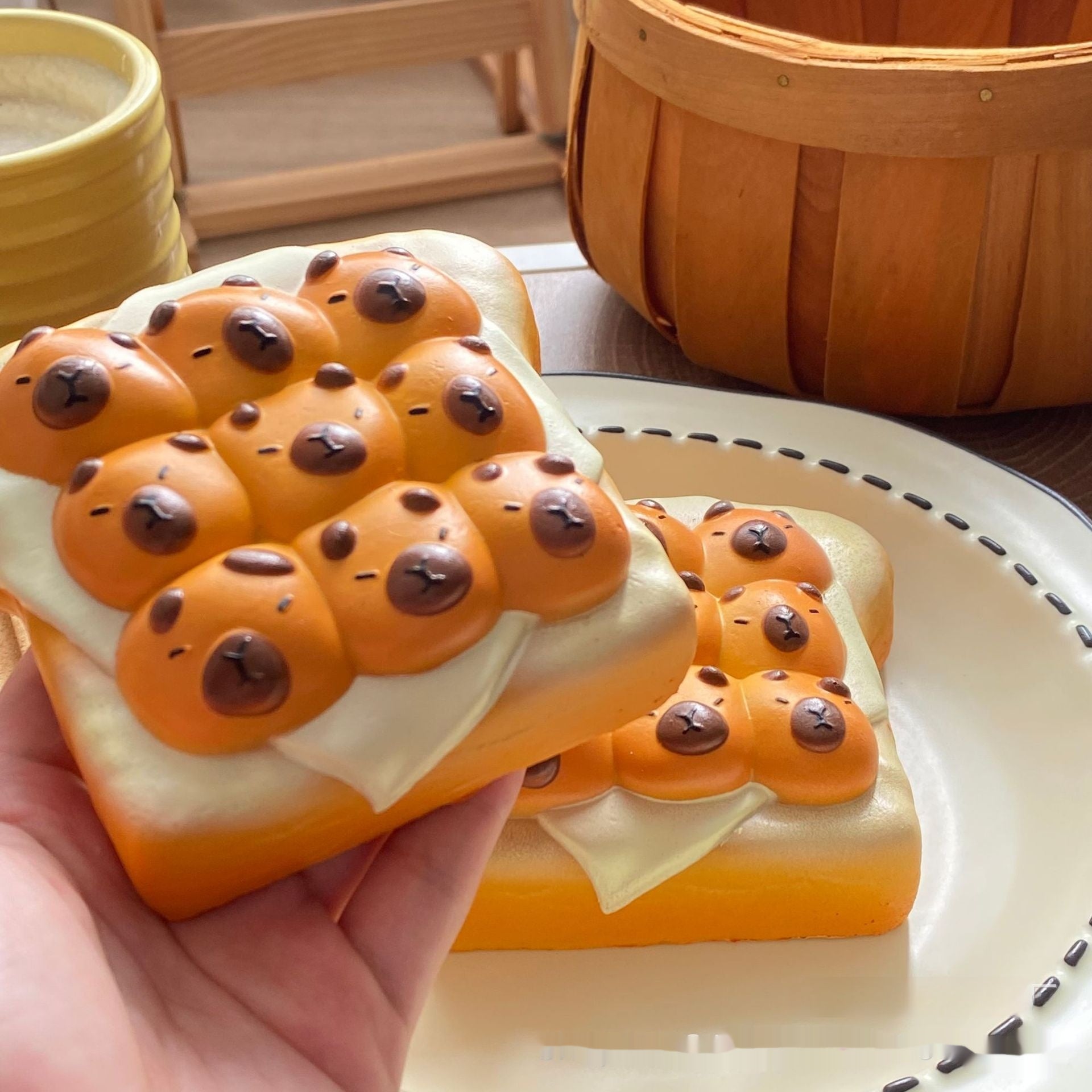 Bread with cartoonish animal faces on a plate, held by a hand.