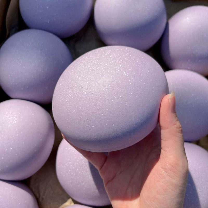 Hand holding a purple glittery ball with more purple balls in the background