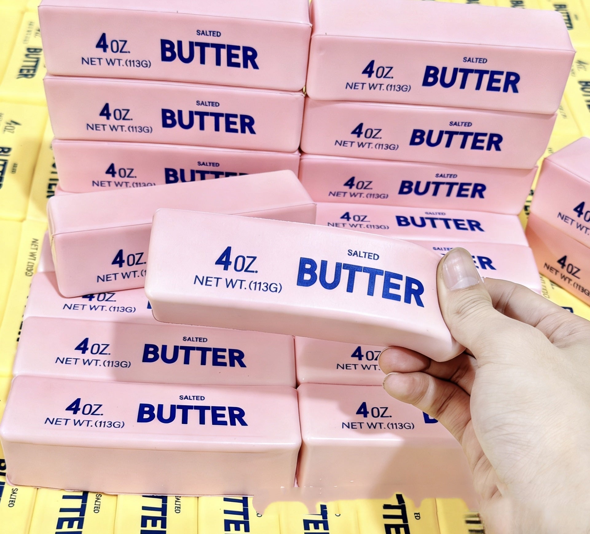 Stack of pink butter squishy with blue text on a yellow background