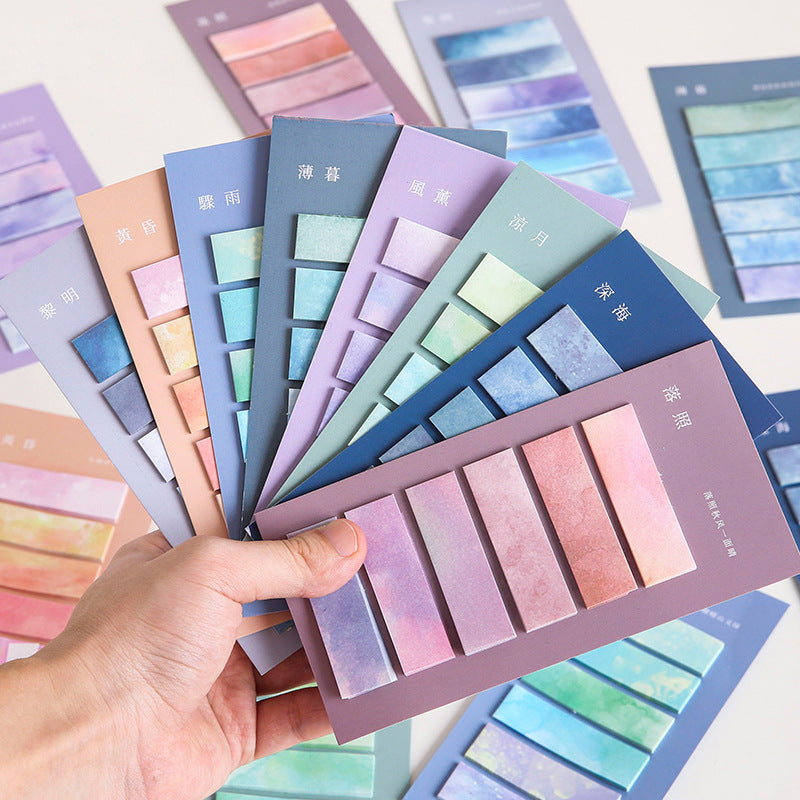 Color swatch cards with pastel shades held by a hand, surrounded by more swatch cards.