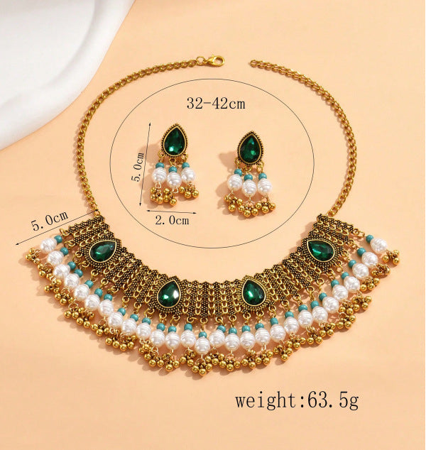 Gold necklace with green and white stones on a beige background