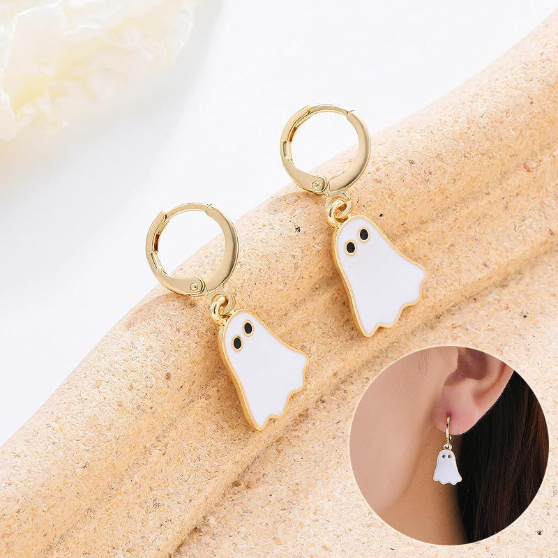 Ghost-shaped earrings on a beige surface with an inset showing an ear wearing one.