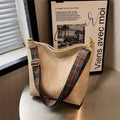 Beige handbag with patterned strap on a surface next to a book titled 'Viens avec moi'.