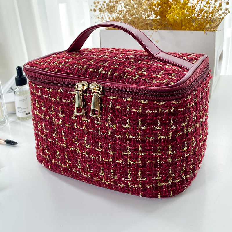 Red and gold patterned cosmetic bag on a white surface with a blurred background