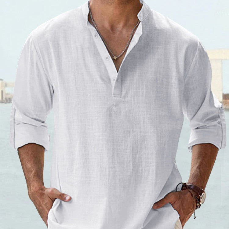 Man wearing a white linen shirt with rolled-up sleeves against a light background