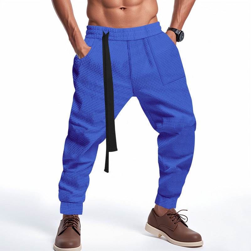 Blue jogger pants with a black drawstring on a white background