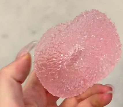Pink textured ball Squishy held by a hand against a neutral background