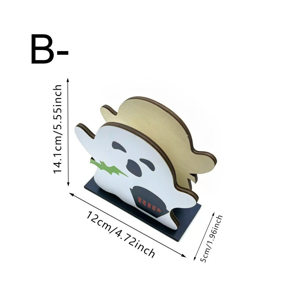 A ghost-shaped tabletop decor piece with a white face, black outlines, green leaf detail, and a tan hat, shown on a black base with dimension arrows and text indicating 14.1 cm tall, 12 cm wide, and 5 cm deep.