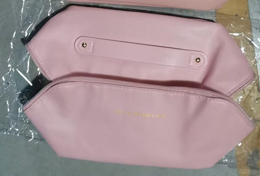 Pink pouch with gold text on a gray surface