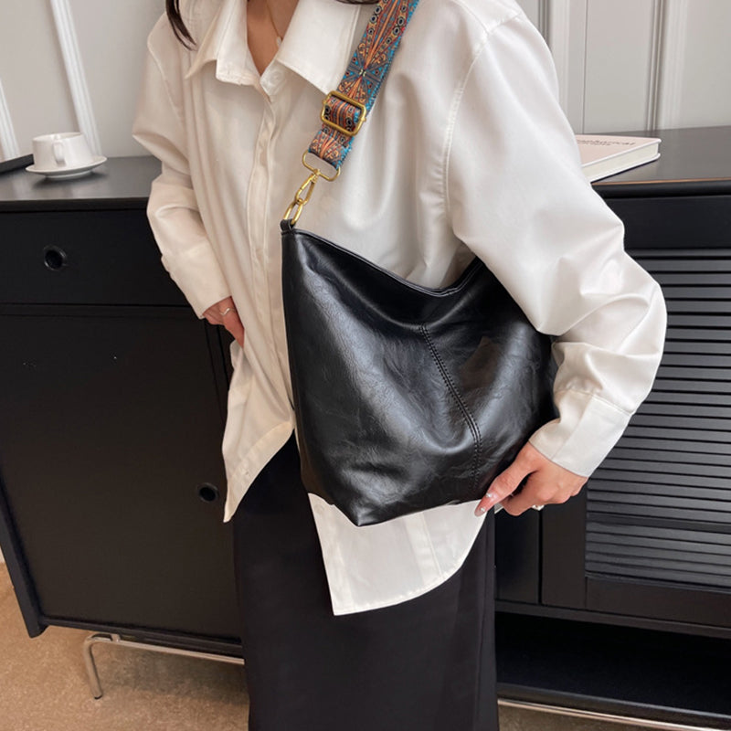 Person holding a black leather bag in an indoor setting