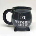 A glossy black cauldron-shaped mug with a white crescent moon and stars graphic and the words 'WITCHES BREW' printed on the front, set against a plain light background.