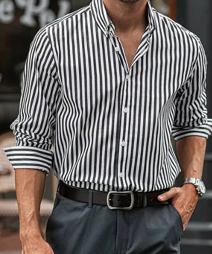 Man wearing a black and white striped shirt with rolled-up sleeves and dark pants.