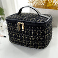 Black and gold checkered makeup bag on a white surface with a blurred background