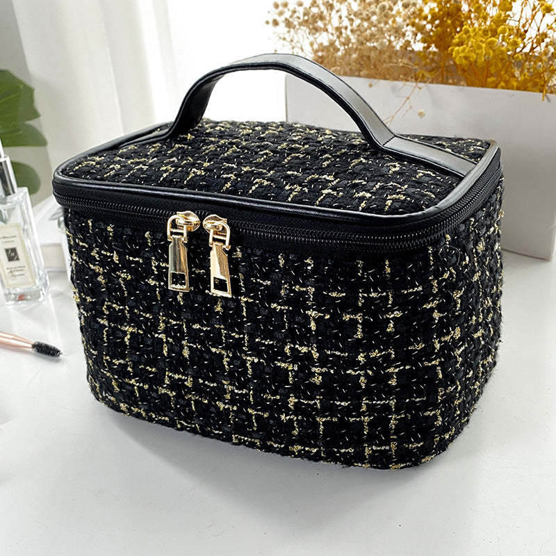 Black and gold checkered makeup bag on a white surface with a blurred background