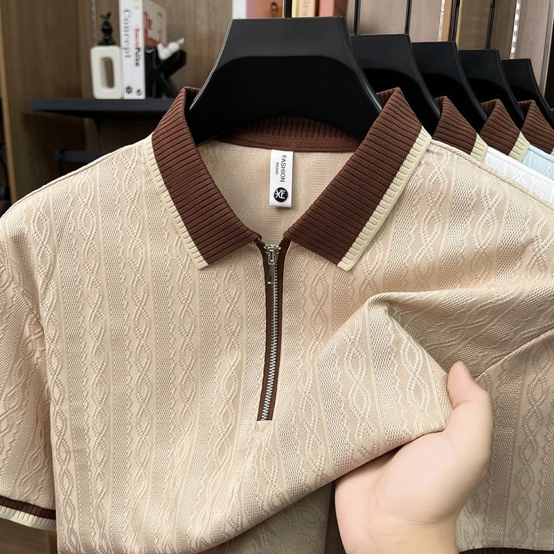 Beige sweater with brown collar and zipper held by a hand, with more sweaters in the background.