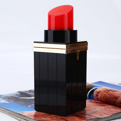 Black lipstick case with red cap on a magazine background