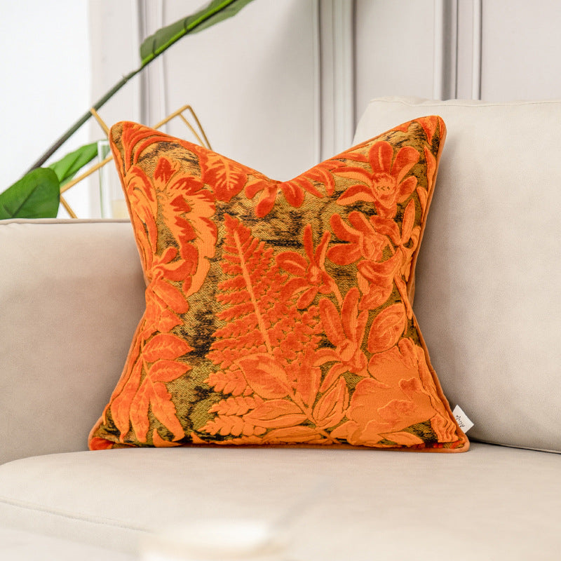 Orange floral pillow on a beige sofa with a neutral background
