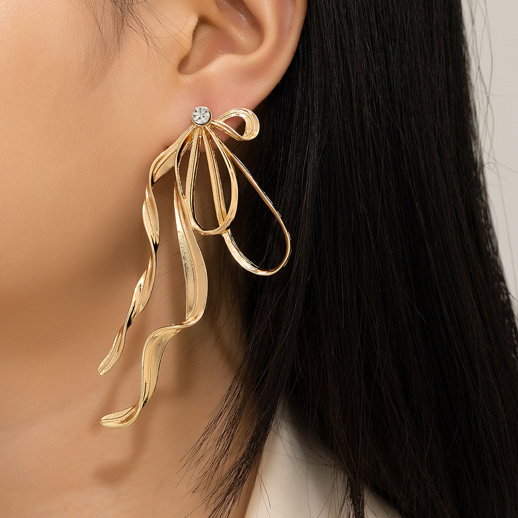 Gold leaf-shaped earring worn by a person with dark hair.