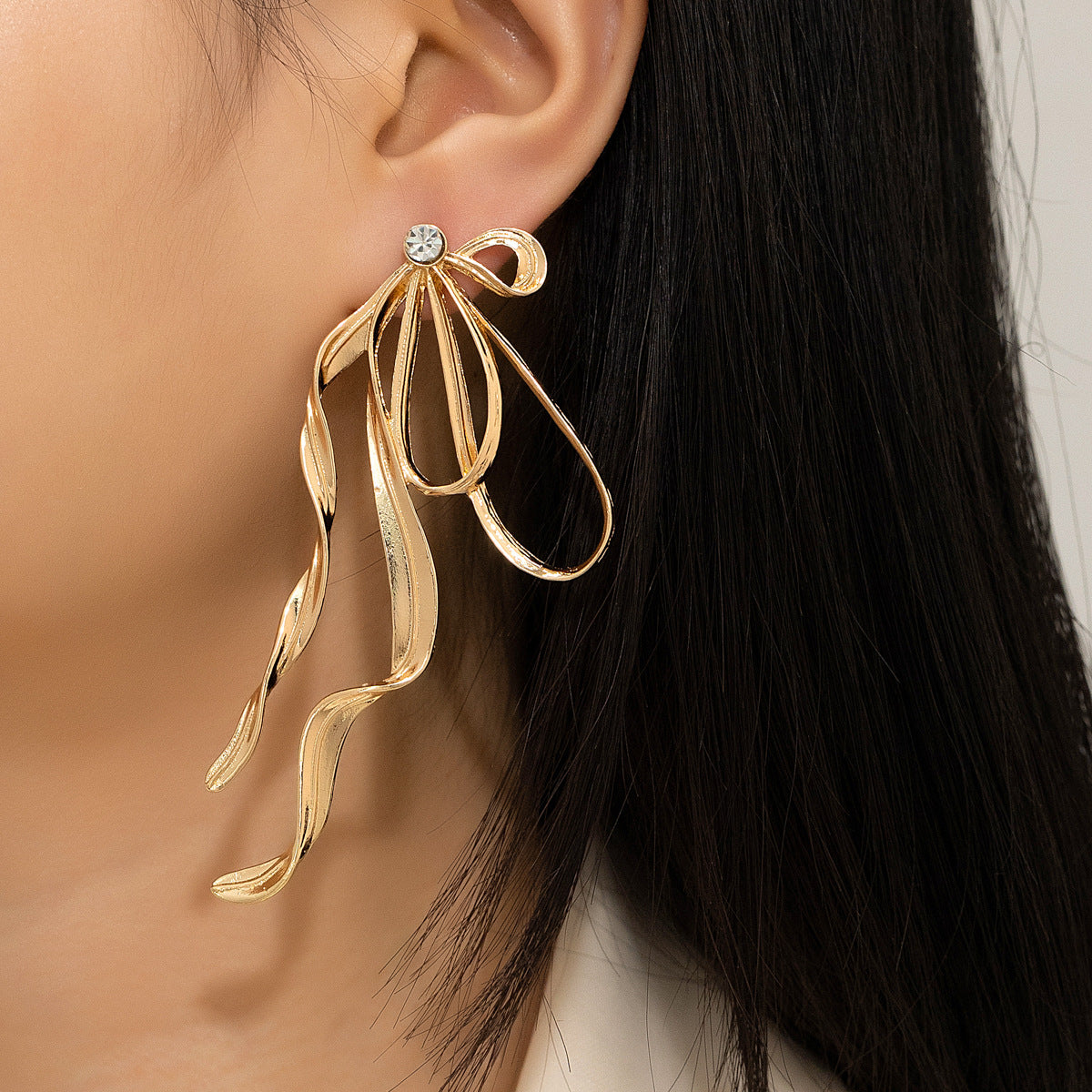 Gold leaf-shaped earring worn by a person with dark hair.