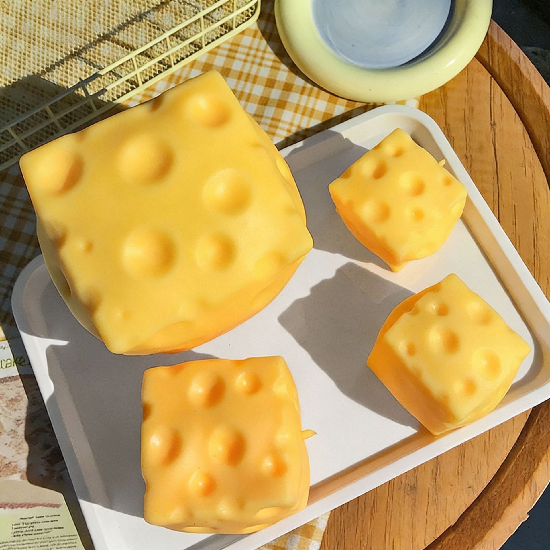 Cheese-shaped ice cubes squishy on a tray with a checkered cloth background