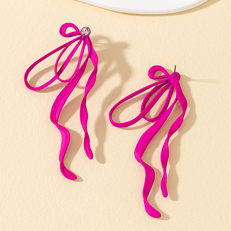 Pink ribbon earrings on a beige background