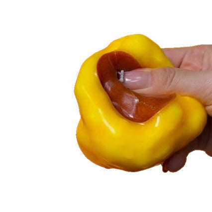 A hand holding a yellow acorn-shaped squishy toy against a plain white background.