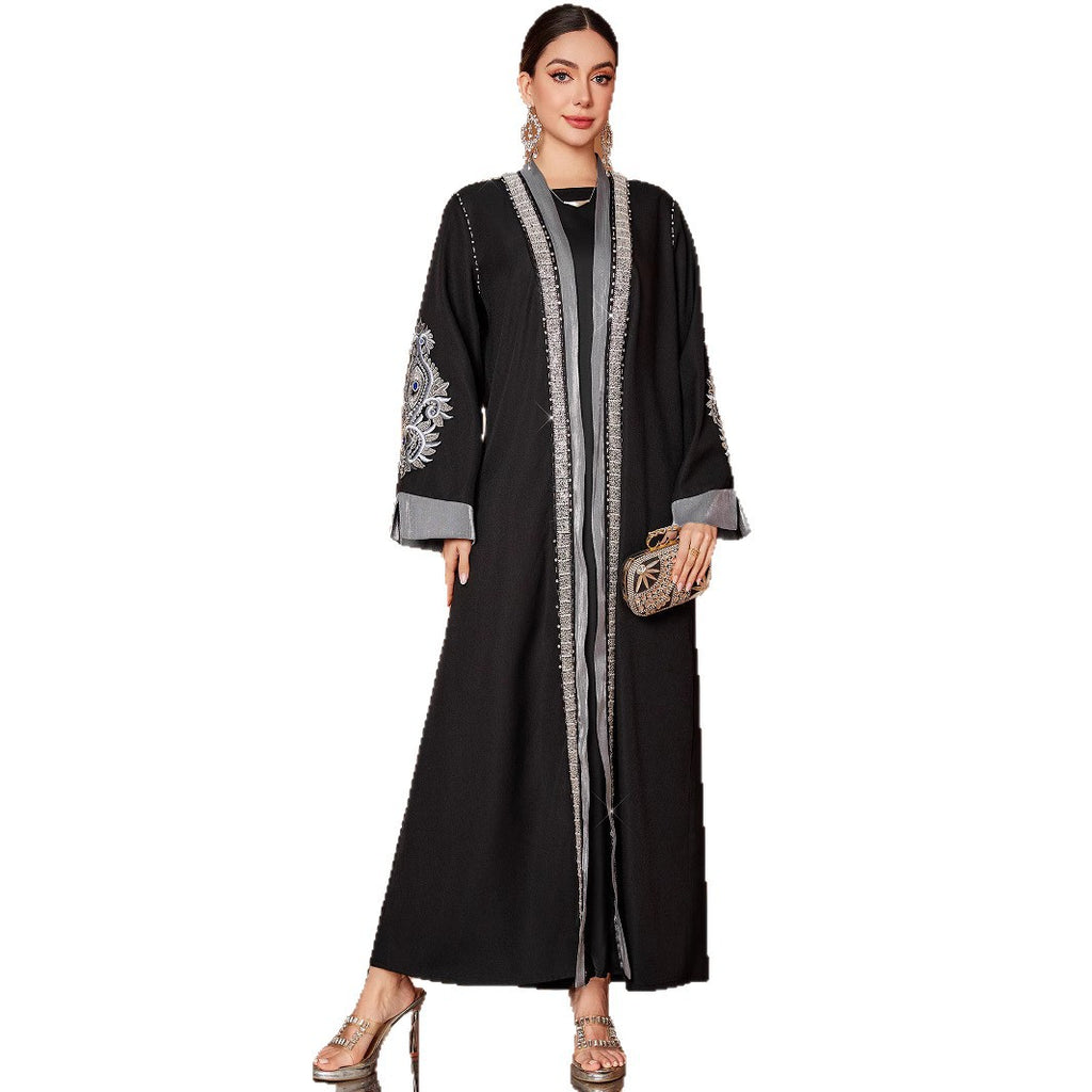 Woman wearing a black abaya with white embroidery on a white background