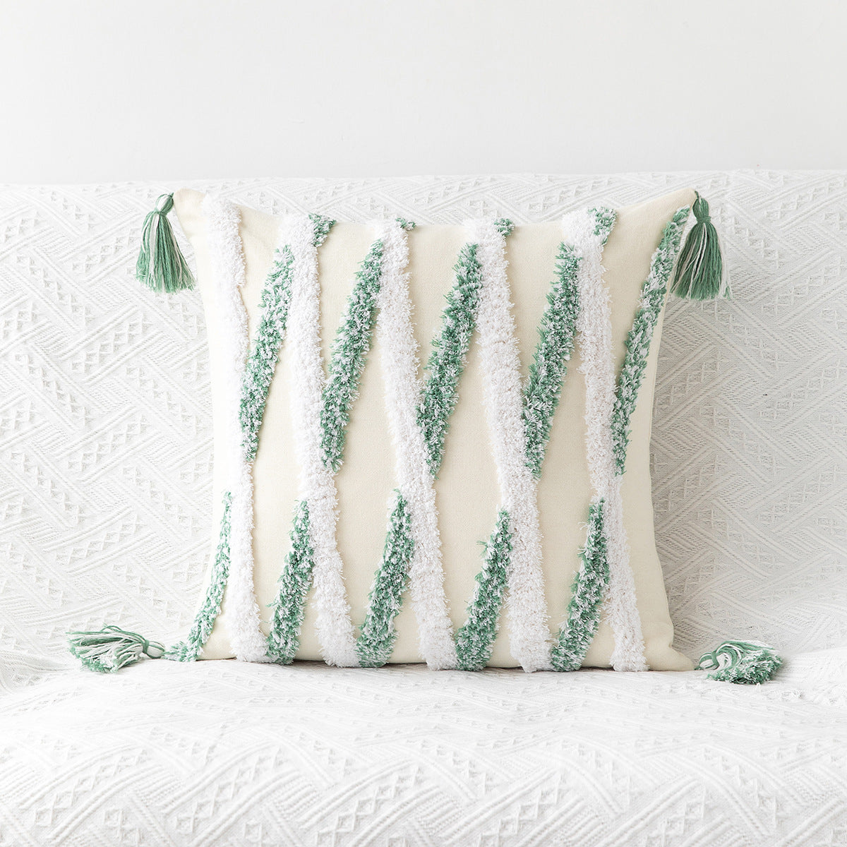 Decorative pillow with green tassels on a textured white background